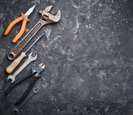 Copy space of working tools on a black concrete surface. Nippers, wrench keys, pliers, screwdriver. Top view.の写真素材