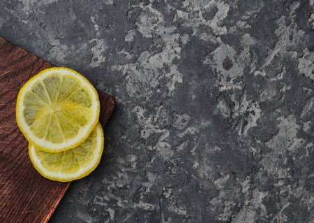 Two slices of lemon on a wooden board lie on a concrete table. Top view.の写真素材