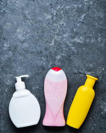 Bottles of products for showering on a black concrete surface. shampoo, soap, shower gel. Copy space. Top view. Flat lay.の写真素材