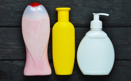 Bottles of products for shower. Shower gel, liquid soap, shampoo on a black wooden table. Top view.の写真素材