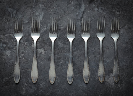 A lot of steel spoons on a black concrete table. Top view. Kitchen cutlery.の写真素材