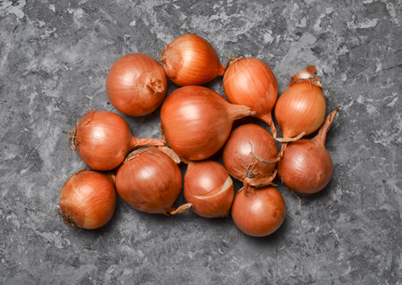 Many onions on a gray concrete surface. Useful vegetables.