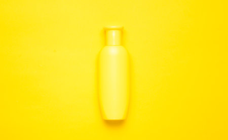 Yellow bottle of shampoo on a yellow background. Trend of minimalism. Top view. Products for the shower. Space for text.の写真素材