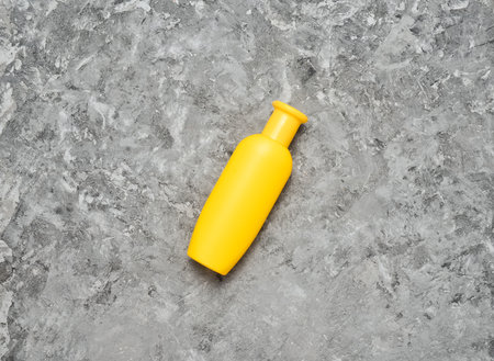 A yellow bottle of shampoo on a gray concrete table. Trend of minimalism. Top view. Products for the shower. Space for text.の写真素材