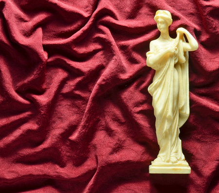Antique souvenir statue of the Greek goddess on a red silk background. Copy space.の写真素材