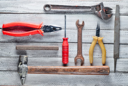 Working tool on a white wooden background: screwdriver, pliers, scrap, hammer, nippers, file, adjustable wrench. Top view.の写真素材