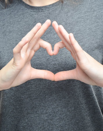 A symbol of the heart with the fingers of a female hand.の写真素材