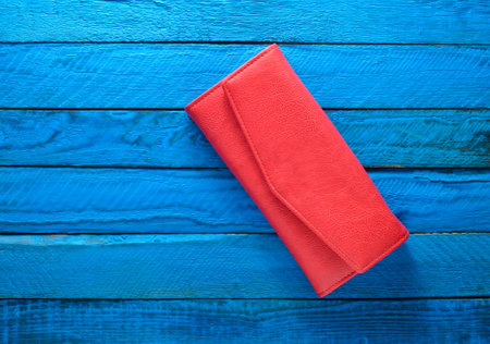 Fashionable red purse on a blue wooden background. Top view. Trend of minimalism.