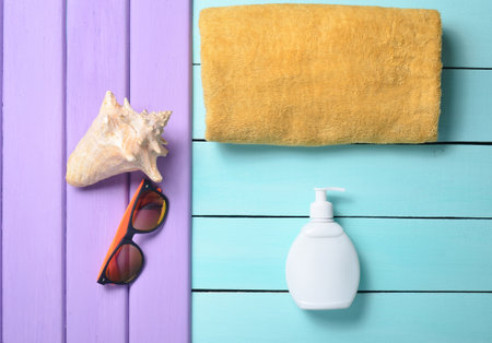 Products and accessories for relaxing on the beach: sunblock, towel, sunglasses, shell on a...