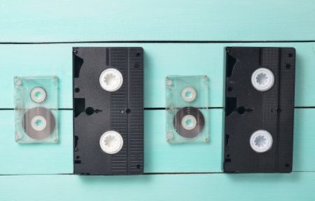 Video cassettes and audio cassettes on a turquoise wooden table. Retro video and audio technology. Top view.の写真素材