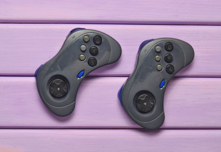 Two wireless gamepad on a purple wooden table. Top view.の写真素材