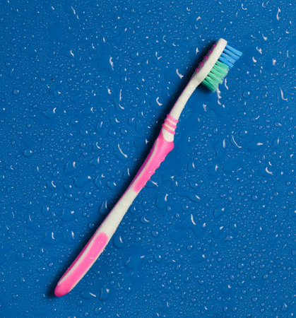 A toothbrush in drops of water on a blue background. Top view.の写真素材
