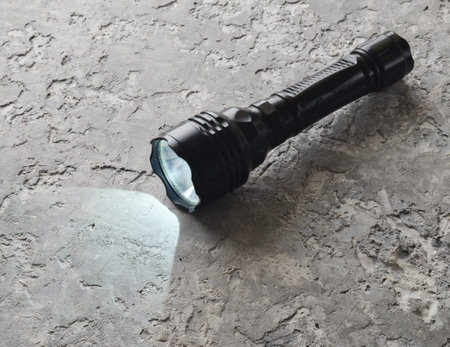 A glowing flashlight on a gray concrete table.
