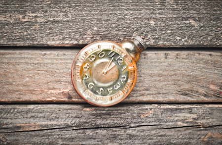 Vintage old Christmas tree toy in the form of a clock on a rustic wooden table. Top view.