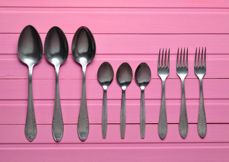 A group of forks, a spoons on a pink wooden table. Cutlery. Top view.の写真素材