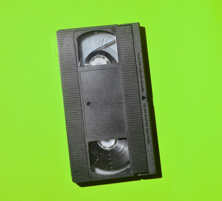 Retro videocassette from 80s on a green background. Obsolete media technologies.