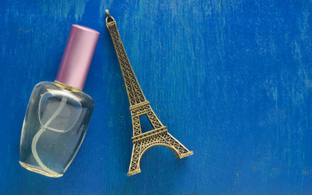 A perfume bottle and a souvenir statuette of the Eiffel Tower on a blue background.の写真素材