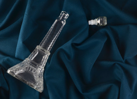 Empty glass vessel in the form of an eiffel tower on a dark cloth tablecloth.
