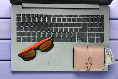 The concept of web work at a beach resort, freelancing. Laptop, sunglasses, purse on a violet color wooden table. Top view.の写真素材