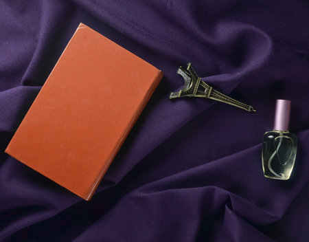 The concept of love of reading, the desire to travel to France. The book, a statuette of the Eiffel Tower, a bottle of perfume on a dark sheet. Top view.の写真素材