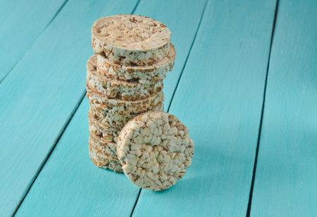 Crispy round dietary buckwheat rice fitness bread wrapped with a ruler on blue wooden table. Food for weight loss.の写真素材
