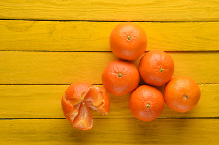 A lot of ripe mandarins on a yellow wooden table. Top view. Fruit concept.の写真素材