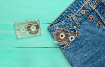 Two audio cassettes in a jeans pocket on a blue wooden surface. Media technology from the 80s.の写真素材