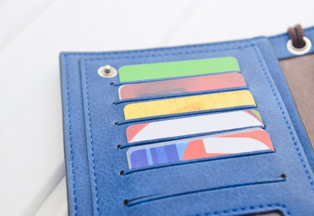 Wallet with credit cards on a white wooden table.