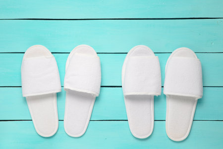 Two pairs of hotel white slippers on a blue wooden floor. Top view.の写真素材