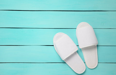 Hotel white slippers on a blue wooden floor. Top view.の写真素材