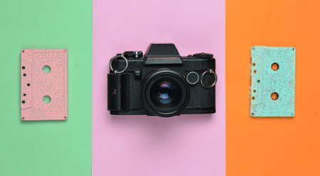 A retro audio cassette tape pastel color and a film camera on a colored paper background. Copy space. Minimalist trend.の写真素材