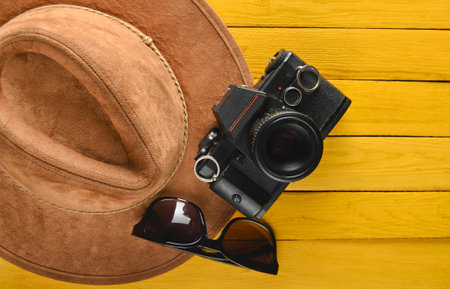Felt hat, film camera, sunglasses layout on a colored wooden background. Passion for travel, wanderlust concept. Flat lay.の写真素材