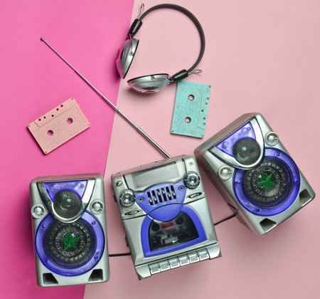 Vintage tape recorder, wireless headphones, audio cassettes on a pastel background. Top view, flat...