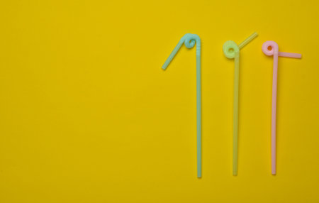 Colored cocktail tubes on a yellow pastel background. Top view. Copy space. Minimalist trend.の写真素材