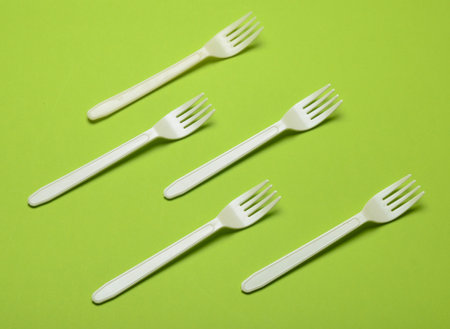 Plastic fork for a picnic on a green background. Minimalist trend. Top view.