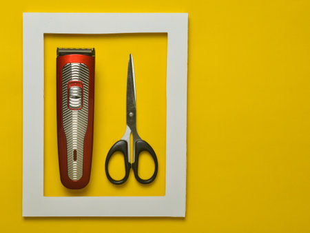 The machine for a hairstyle and scissors in a white frame on a yellow background. Minimalist trend....
