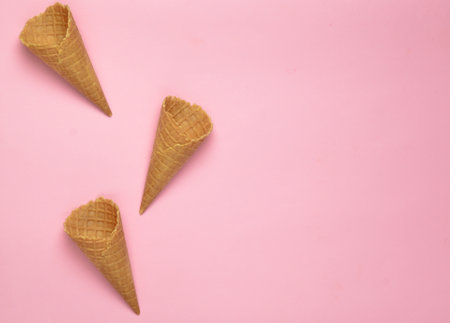 Empty waffle horns on a pink background, copy space. Top view, creative background, minimalist trendの写真素材