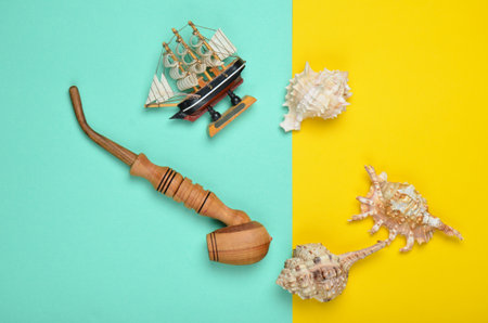 Decorative ship, seashells, chicken pipe on a colored pastel background. Captain shipwreck. Summer...