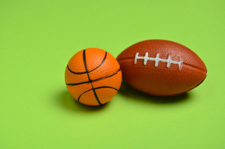 Miniature souvenir balls of American football and basketball on a green backgroundの写真素材
