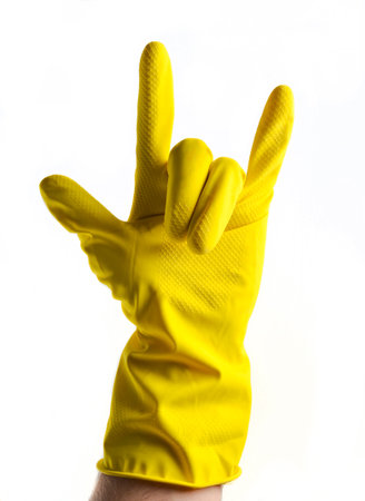 A hand in yellow rubber gloves shows a rock horn, two fingers up on a white backgroundの写真素材