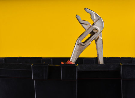 Adjustable wrench in black plastic tool box isolated on yellowの写真素材