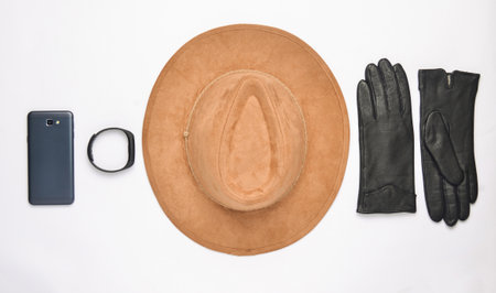 Female accessories and gadgets on a white background. Hat, gloves, smartphone, smart watch. Autumn...