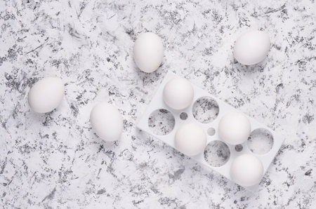 Plastic tray with white eggs on a white concrete background, minimalism trend, top viewの写真素材