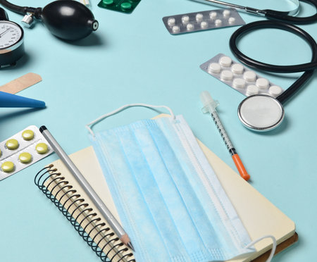 Medical equipment on a blue background. Enema, blisters pills, notepad, stethoscope, syringe, thermometer, manometer. Medical concept, copy spaceの写真素材