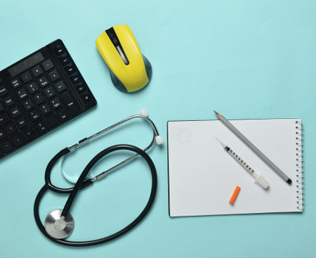 Workplace of a modern doctor. Keyboard, wireless mouse, notebook, stethoscope, syringe on a blue...