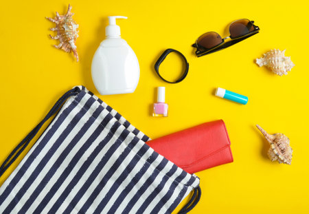 Beach bag and accessories for relaxing on the beach layout on yellow pastel background. The concept...