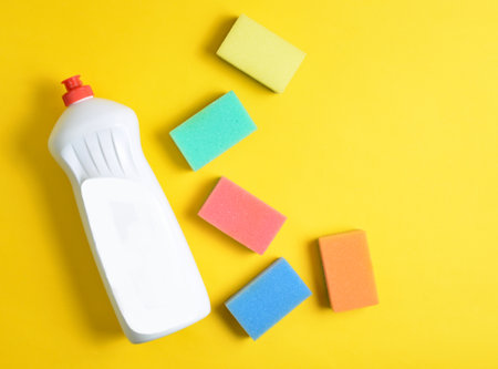 Plastic bottle of dishwashing detergent, sponges on yellow pastel background, top view, flat lay, minimalismの写真素材