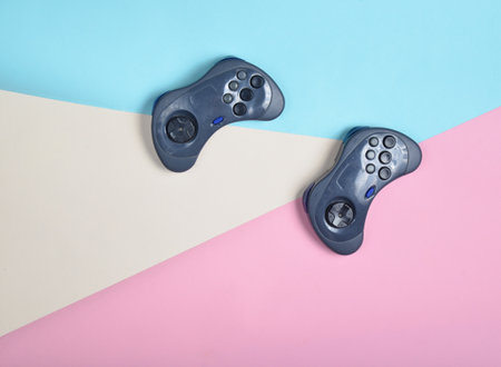 Two gamepads on a multi-colored pastel background. Top view, minimalism
