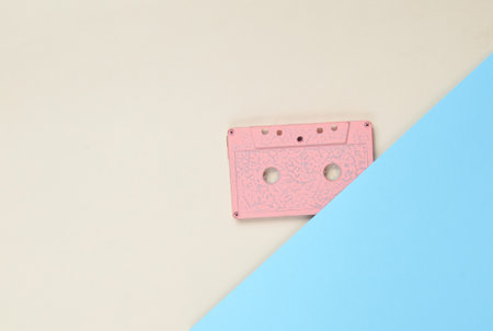 Audio cassette on a colored paper background. Retro media technology 80s. Music, entertainment. Top...