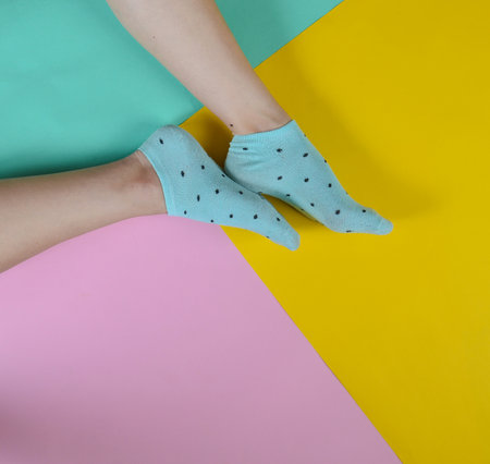 Naked female feet in socks posing on a multi-colored paper background. Top view.の写真素材
